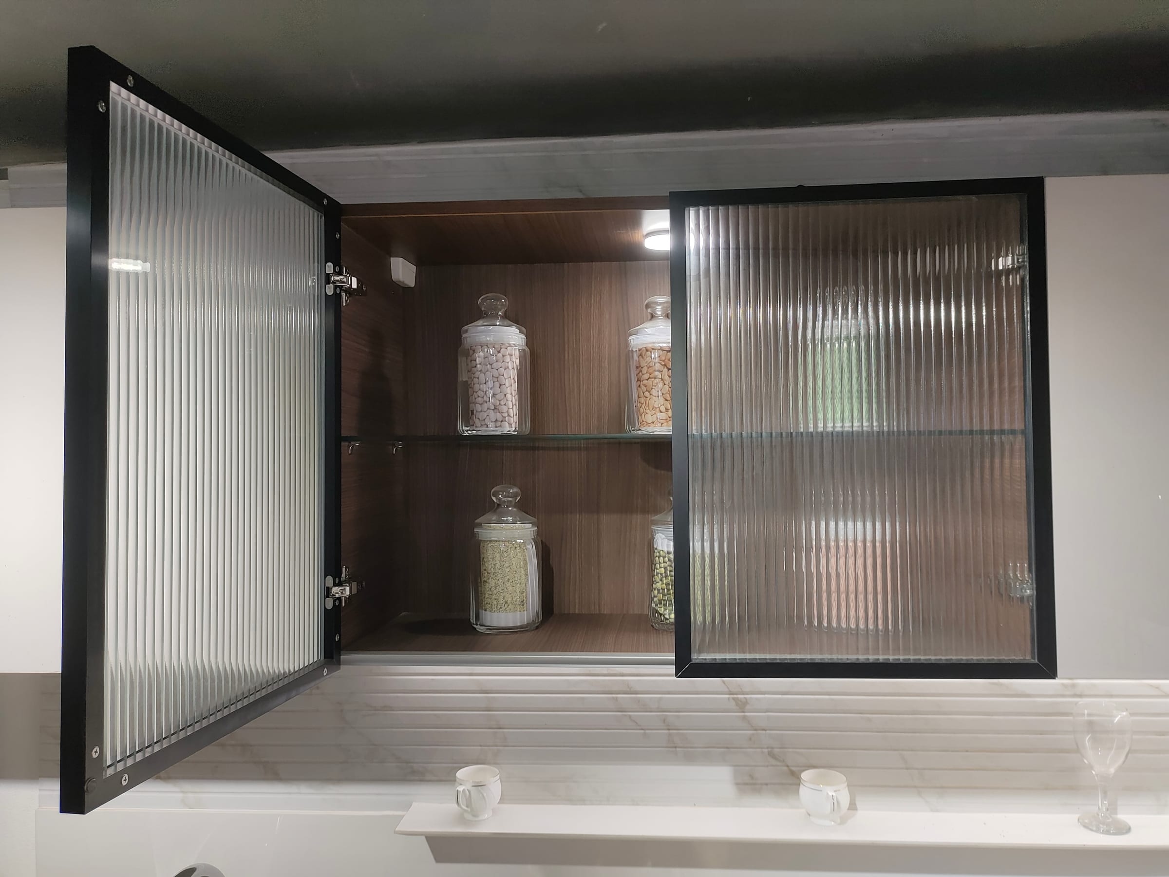 Wall cabinets fronted in reeded glass set into slim black aluminium profile frames