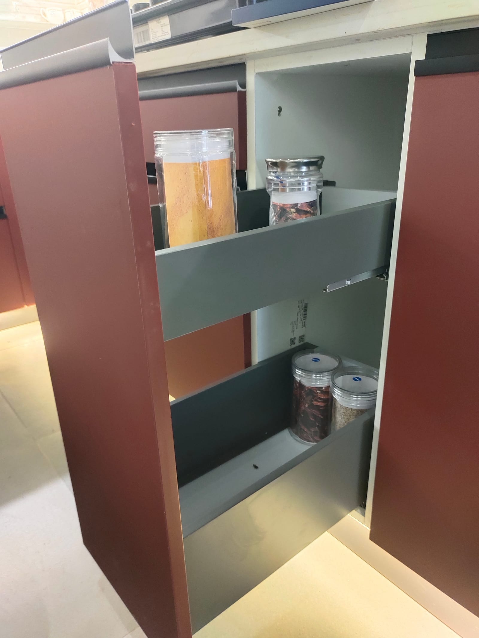 A narrow two-tier wire pull-out drawn out of a base unit, holding bottles and spice containers