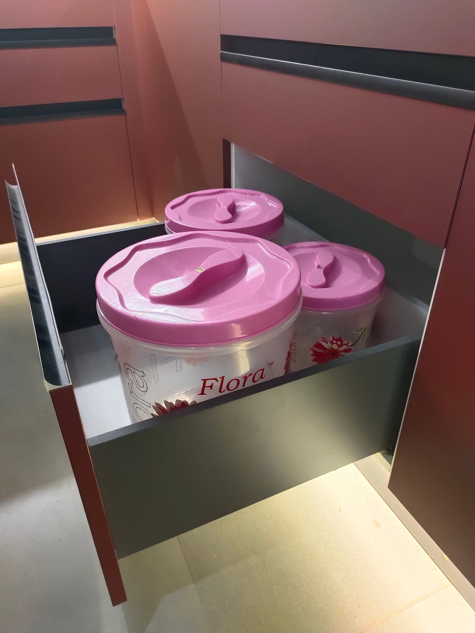 A deep steel-sided drawer box pulled fully open, holding stacked food containers