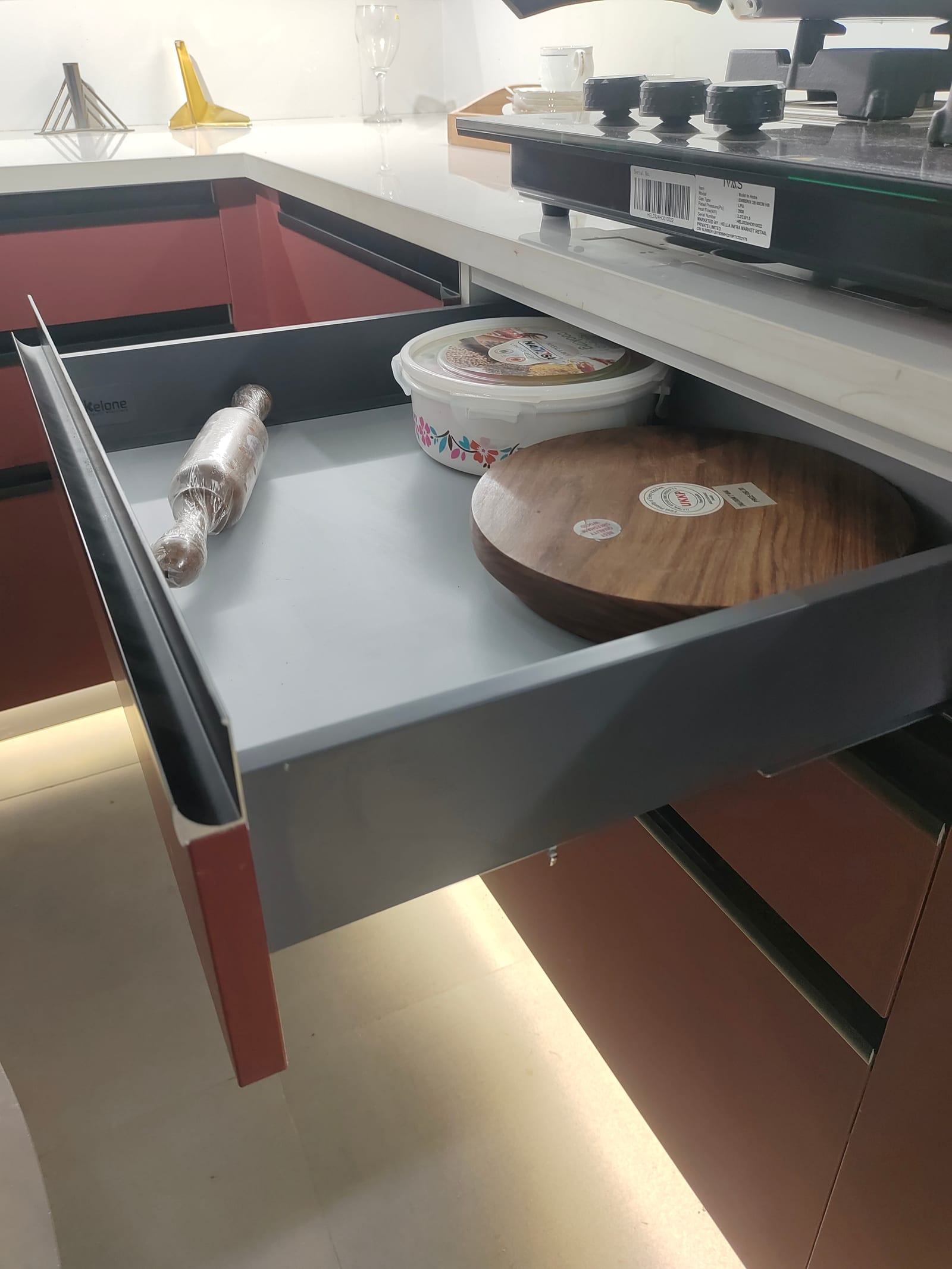 A shallow steel-sided drawer box open in the base unit directly beneath a hob