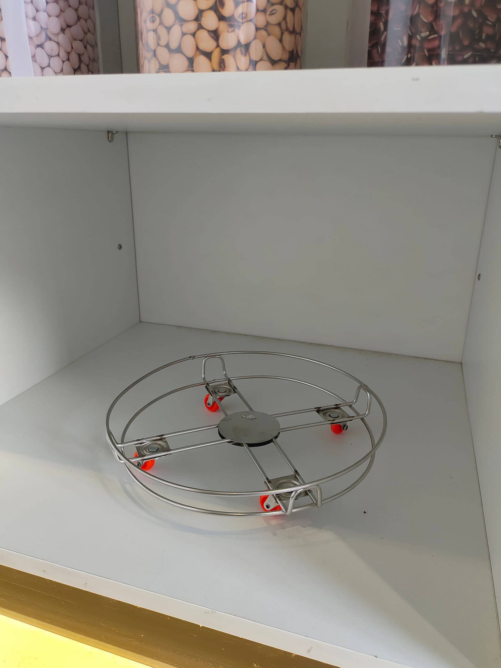 A round wire trolley on castors inside a base unit, sized to take a domestic gas cylinder