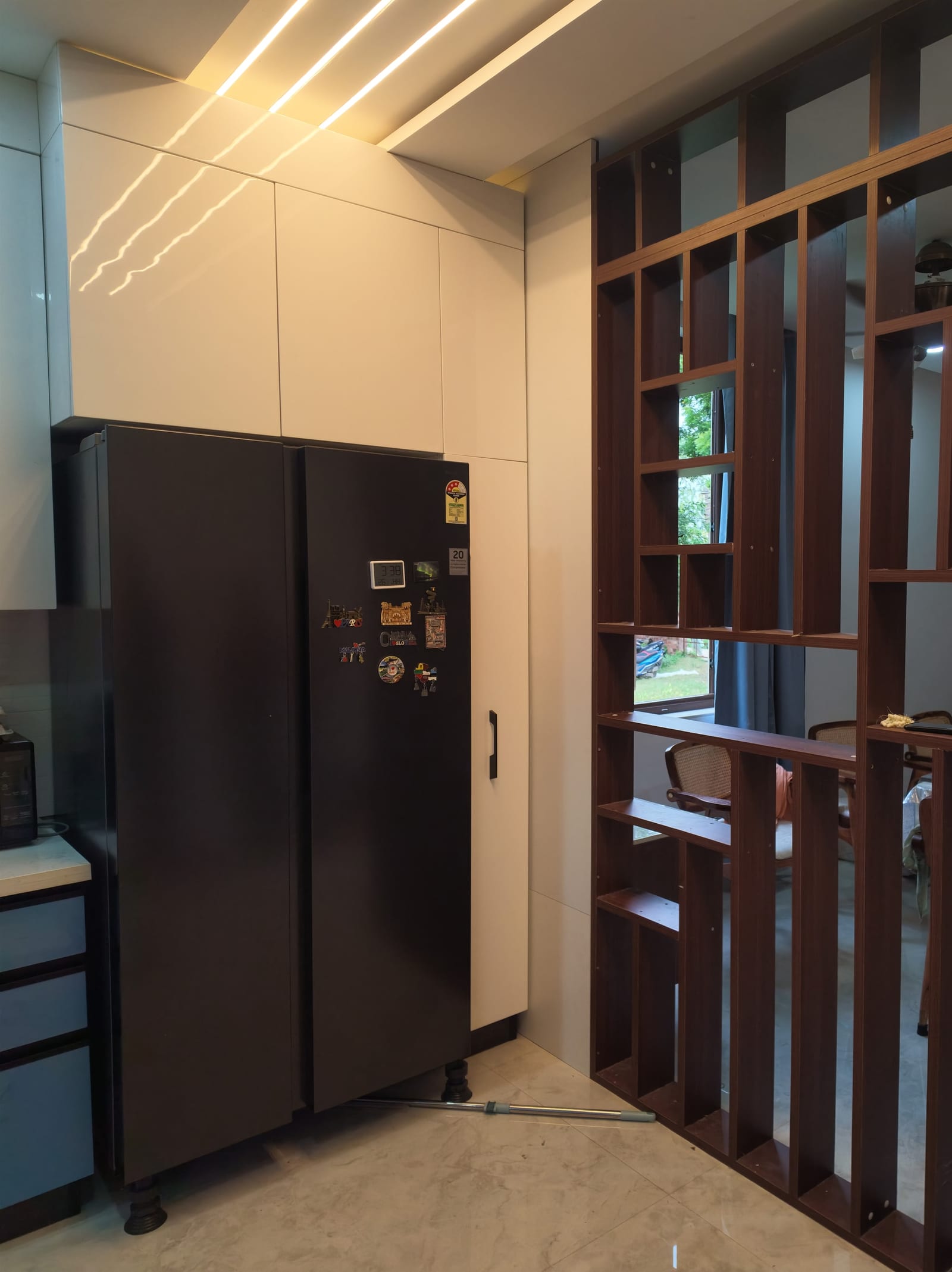 An open wooden screen with irregular shelving, separating a kitchen from the dining room